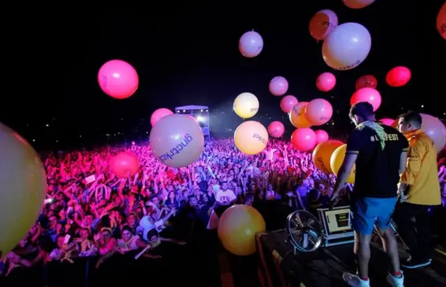 Gece konserinde sahneden kalabalığın üzerine atılan renkli balonlar