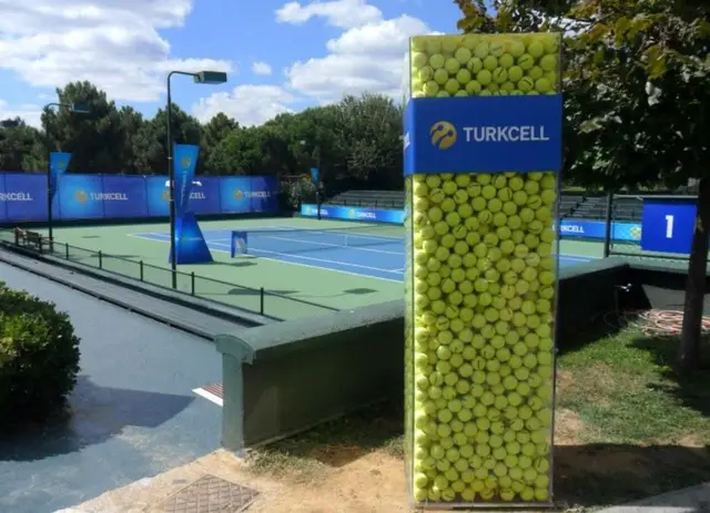 Turkcell logolu tenis kortu panoları ve tenis toplarıyla doldurulmuş kule