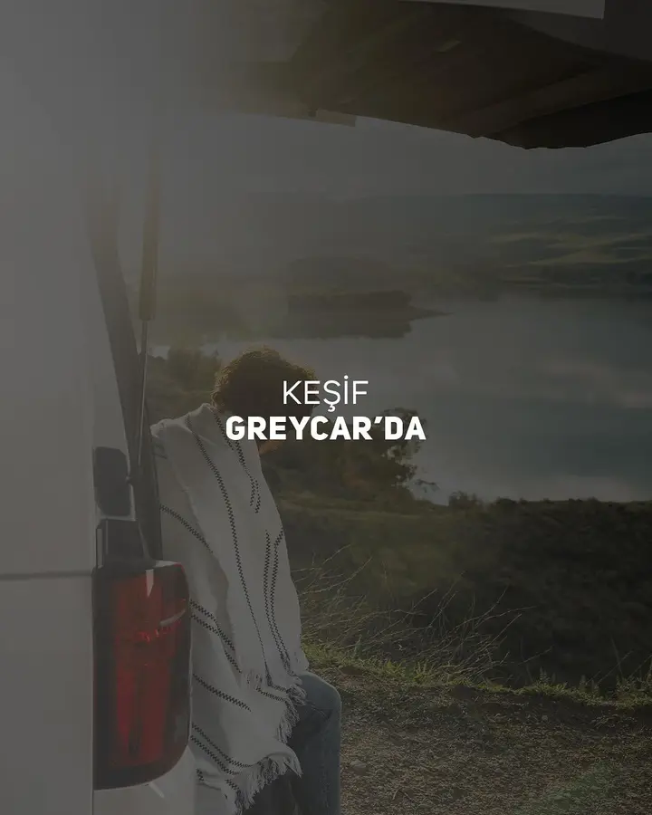 Bagaj kapağı açık bir aracın yanında göl manzarasına bakan kişi; üzerinde “Keşif GREYCAR’da” yazıyor